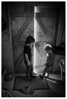 grandsons opening the door of in the wooden shed in their grandfather's garden